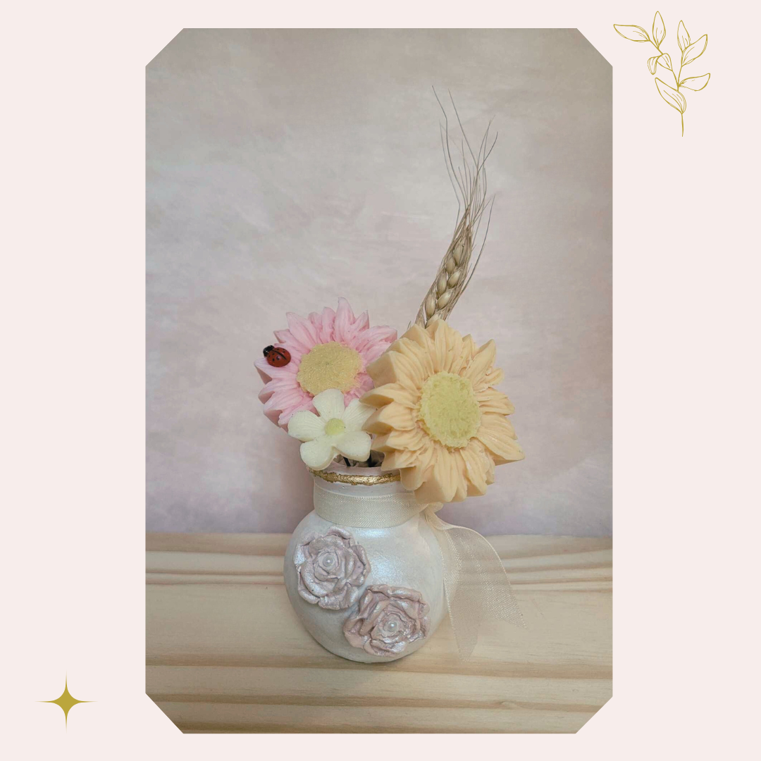 Bouquet décoratif parfumé “Promesse d’un matin”, composé de fleurs en cire dans des teintes beige crème, rose tendre et abricot poudré, présenté dans un pot en plâtre de porcelaine blanc. Une création artisanale faite main en Corse, inspirée par la douceur des souvenirs d’enfance.